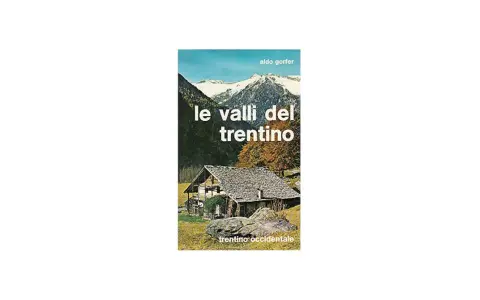 Copertina del libro "Le valli del Trentino" di Aldo Gorfer, con un casolare in pietra e tetto spiovente, montagne innevate sullo sfondo e alberi autunnali.