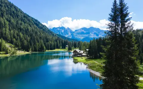 Incantevole lago alpino vicino a Madonna di Campiglio, con boschi rigogliosi, montagne maestose e un rifugio accogliente.