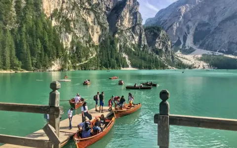 Gente in barca sul lago di Braies, dove si trova questo gioiello alpino. Montagne imponenti e acque turchesi.