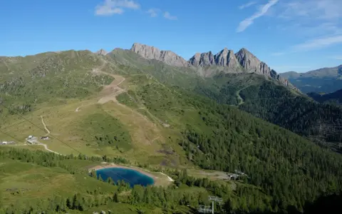 Panorami mozzafiato per passeggiate facili vicino a Trento. Un lago alpino azzurro e sentieri tra prati e boschi.