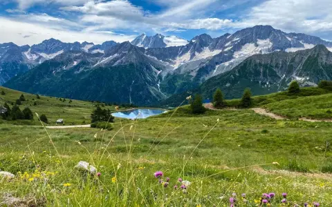 Un incantevole passo tra Lombardia e Trentino, con un lago alpino specchiato e montagne innevate sullo sfondo.