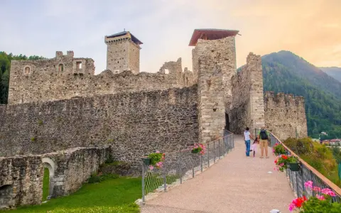 Castello di Stenico, uno dei tanti paesi da visitare vicino Dimaro, con una famiglia che passeggia sul ponte fiorito.