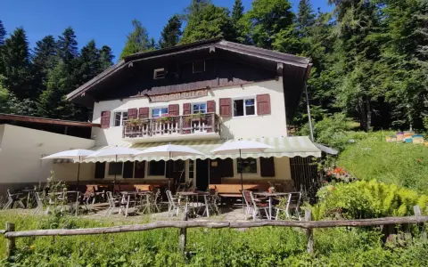 Rifugio alpino con tavoli all'aperto, ideale per rilassarsi dopo le ronzone passeggiate nel bosco.