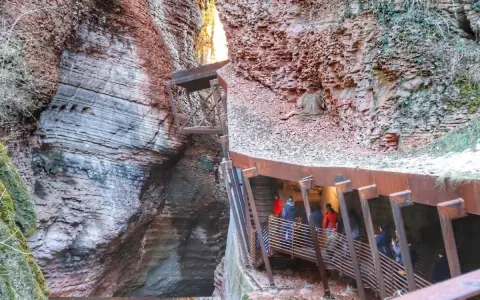 Persone percorrono una passerella metallica lungo le pareti rocciose di un canyon, vicino al Ponte dell'Orrido.