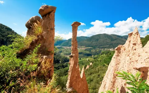 Le Piramidi di Segonzano, un paesaggio unico da esplorare. Le formazioni rocciose scolpite dal tempo dominano la valle verdeggiante.