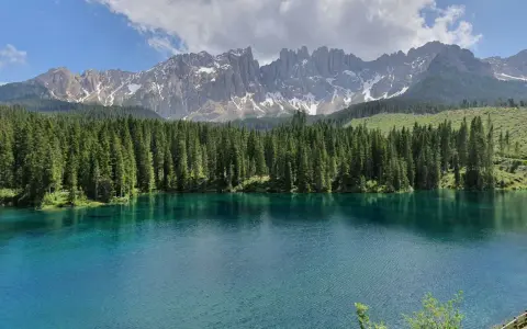 Laghi alpini in Val di Fassa, con acque cristalline che riflettono la foresta di abeti e le maestose cime dolomitiche innevate.