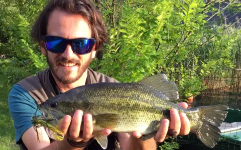 Felice pescatore con un grosso pesce appena pescato al lago di Levico.