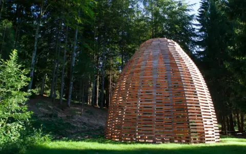 Struttura artistica in legno nel bosco, un'installazione di Arte Sella a Borgo Valsugana.