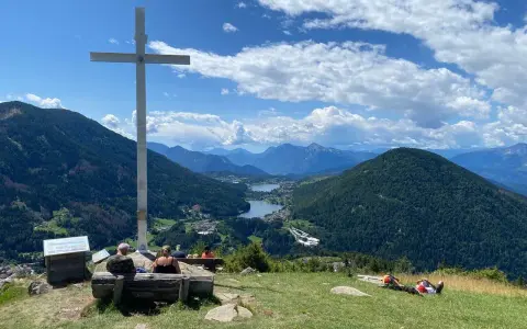 Croce in cima a una collina con vista panoramica su laghi e montagne, nei pressi di Bedollo, Trento.