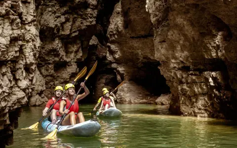 Kayakisti esplorano il suggestivo lago di Santa Giustina canyon, tra pareti rocciose imponenti e acque verdi.