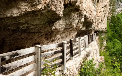 Sentiero panoramico con staccionata in legno lungo la roccia, vicino a Sanzeno San Romedio.