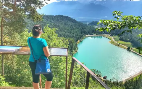 Donna ammira il lago turchese durante una passeggiata della merlonga, con montagne sullo sfondo.