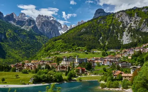 Villaggio alpino con case colorate e lago azzurro, incastonato tra montagne verdi e innevate. Ecco cosa vedere a Molveno per un panorama mozzafiato.
