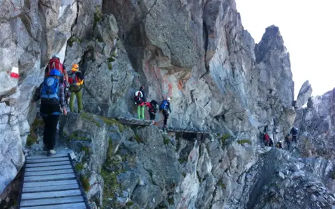 Escursionisti su un sentiero attrezzato, un'avventura di trekking in Adamello tra rocce e passerelle di legno.