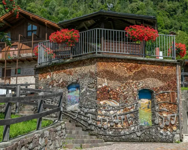 Un edificio unico in montagna, con pareti di legna e dipinti. Un vero spettacolo da vedere a Mezzano, tra natura e arte.