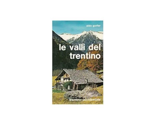 Copertina del libro "Le valli del Trentino" di Aldo Gorfer, con un casolare in pietra e tetto spiovente, montagne innevate sullo sfondo e alberi autunnali.