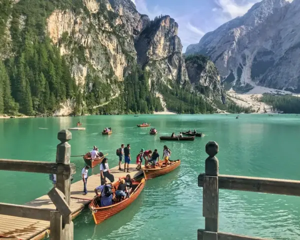 Gente in barca sul lago di Braies, dove si trova questo gioiello alpino. Montagne imponenti e acque turchesi.