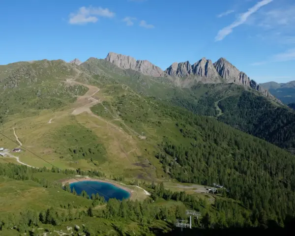 Panorami mozzafiato per passeggiate facili vicino a Trento. Un lago alpino azzurro e sentieri tra prati e boschi.