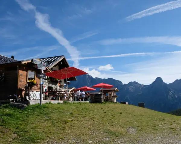 Rifugio alpino con tavoli all'aperto e vista sulle montagne, ideale per il giro delle malghe San Martino di Castrozza.