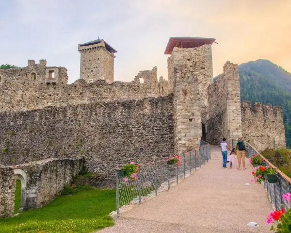 Castello di Stenico, uno dei tanti paesi da visitare vicino Dimaro, con una famiglia che passeggia sul ponte fiorito.