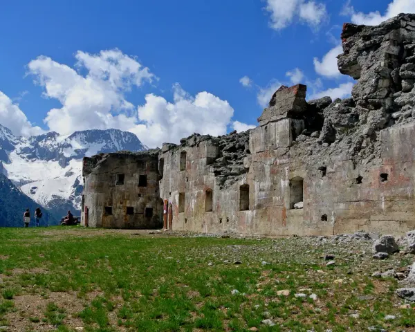 Rovine del forte Zaccarana, con montagne innevate sullo sfondo e cielo azzurro con nuvole bianche.