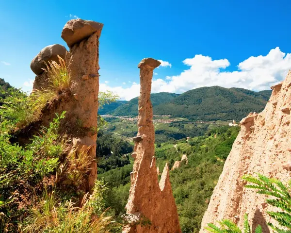 Le Piramidi di Segonzano, un paesaggio unico da esplorare. Le formazioni rocciose scolpite dal tempo dominano la valle verdeggiante.