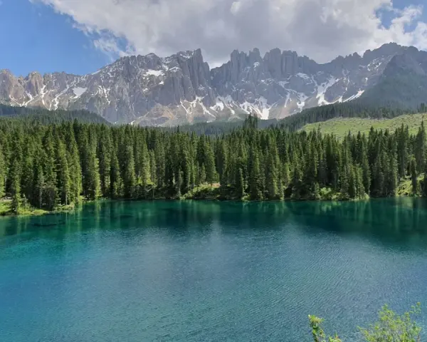 Laghi alpini in Val di Fassa, con acque cristalline che riflettono la foresta di abeti e le maestose cime dolomitiche innevate.