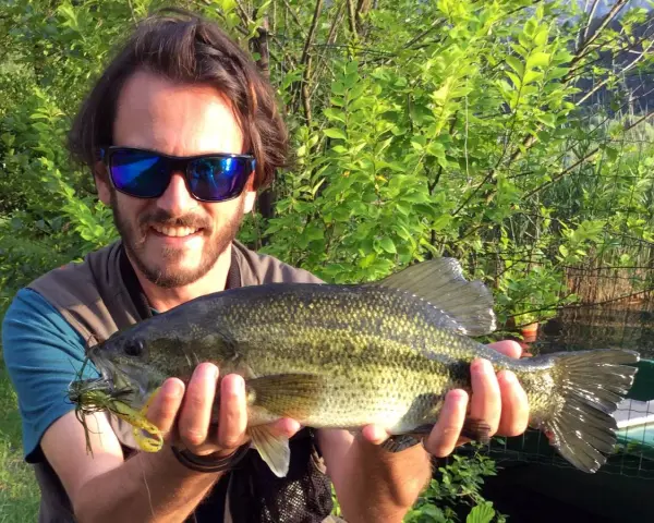 Felice pescatore con un grosso pesce appena pescato al lago di Levico.