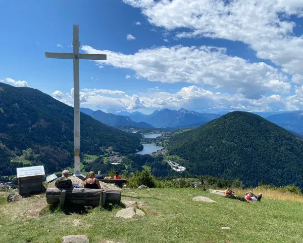 Croce in cima a una collina con vista panoramica su laghi e montagne, nei pressi di Bedollo, Trento.