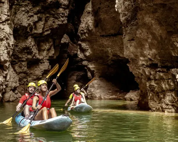 Kayakisti esplorano il suggestivo lago di Santa Giustina canyon, tra pareti rocciose imponenti e acque verdi.
