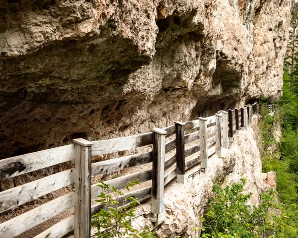 Sentiero panoramico con staccionata in legno lungo la roccia, vicino a Sanzeno San Romedio.