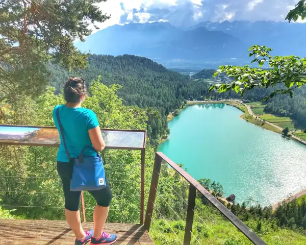 Donna ammira il lago turchese durante una passeggiata della merlonga, con montagne sullo sfondo.