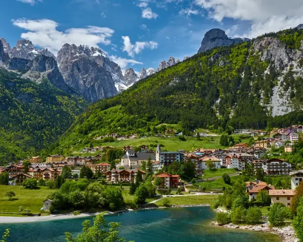 Villaggio alpino con case colorate e lago azzurro, incastonato tra montagne verdi e innevate. Ecco cosa vedere a Molveno per un panorama mozzafiato.