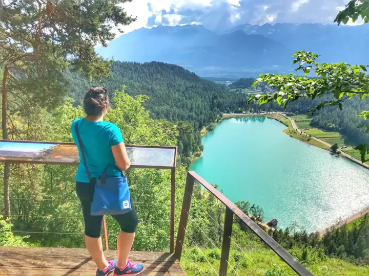 Donna ammira il lago turchese durante una passeggiata della merlonga, con montagne sullo sfondo.