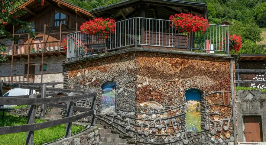 Un edificio unico in montagna, con pareti di legna e dipinti. Un vero spettacolo da vedere a Mezzano, tra natura e arte.