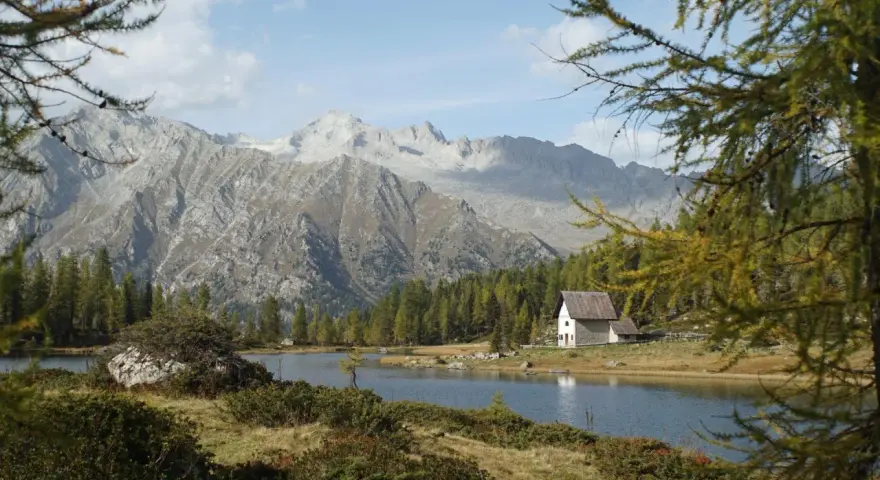 Un rifugio solitario si specchia nei laghi di San Giuliano, circondato da boschi e imponenti montagne.