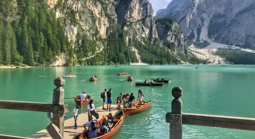 Gente in barca sul lago di Braies, dove si trova questo gioiello alpino. Montagne imponenti e acque turchesi.