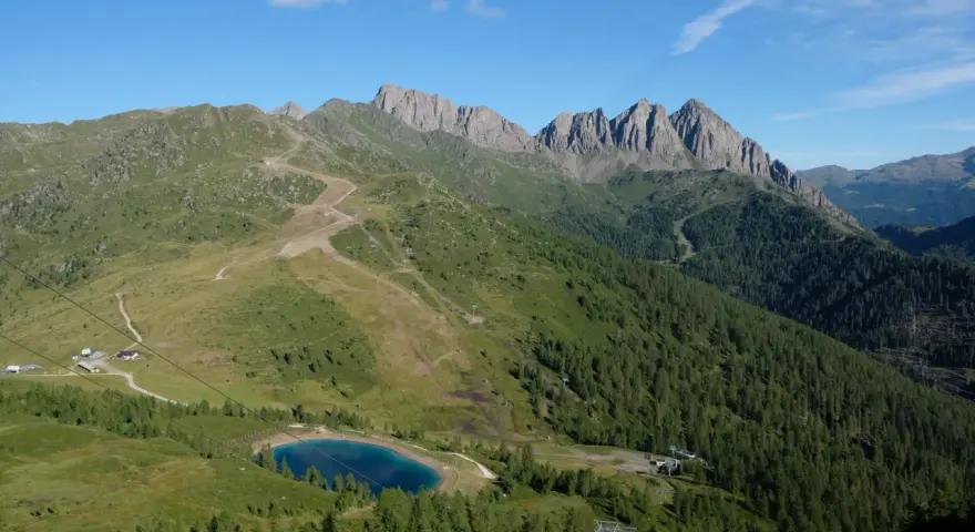 Panorami mozzafiato per passeggiate facili vicino a Trento. Un lago alpino azzurro e sentieri tra prati e boschi.