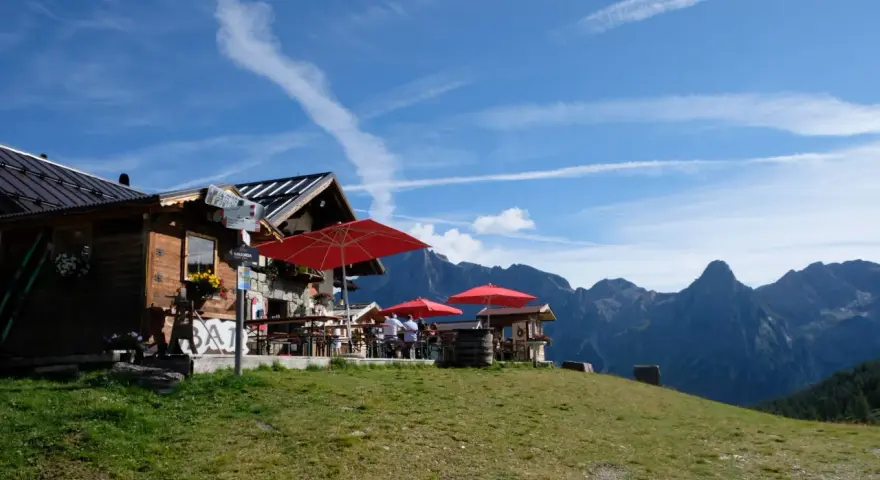 Rifugio alpino con tavoli all'aperto e vista sulle montagne, ideale per il giro delle malghe San Martino di Castrozza.