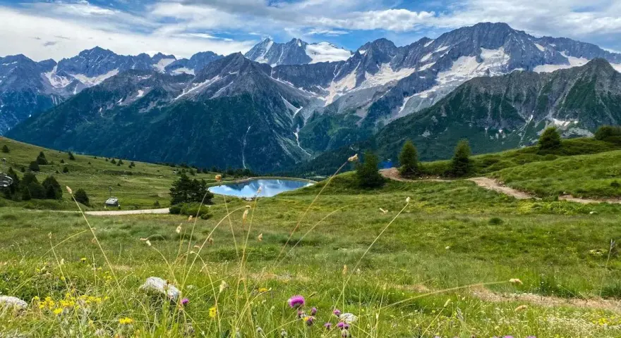Un incantevole passo tra Lombardia e Trentino, con un lago alpino specchiato e montagne innevate sullo sfondo.