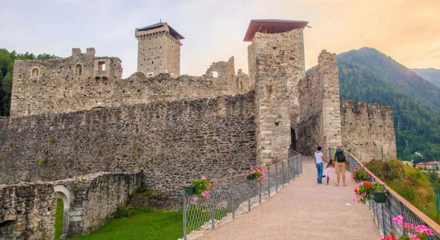 Castello di Stenico, uno dei tanti paesi da visitare vicino Dimaro, con una famiglia che passeggia sul ponte fiorito.