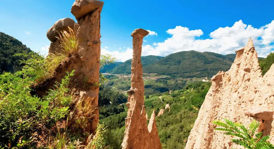 Le Piramidi di Segonzano, un paesaggio unico da esplorare. Le formazioni rocciose scolpite dal tempo dominano la valle verdeggiante.
