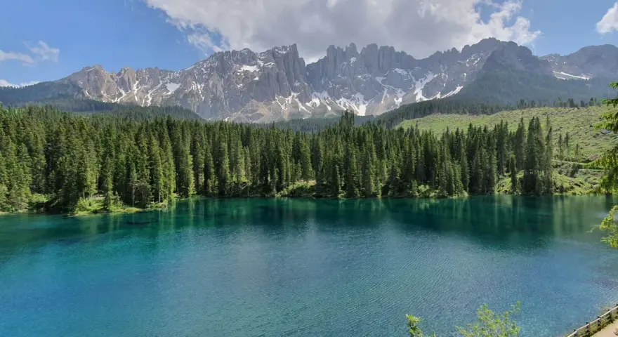 Laghi alpini in Val di Fassa, con acque cristalline che riflettono la foresta di abeti e le maestose cime dolomitiche innevate.