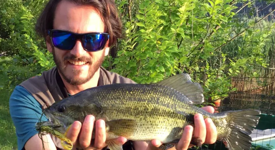 Felice pescatore con un grosso pesce appena pescato al lago di Levico.