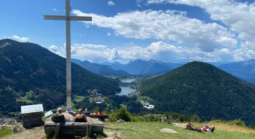 Croce in cima a una collina con vista panoramica su laghi e montagne, nei pressi di Bedollo, Trento.