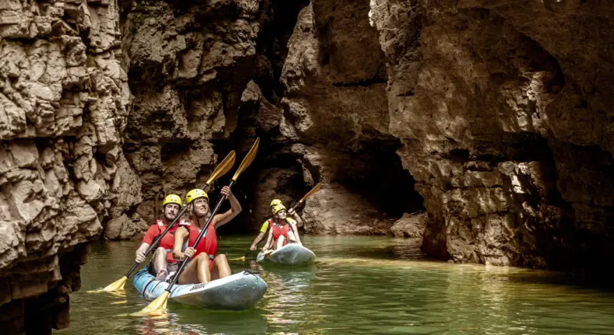 Kayakisti esplorano il suggestivo lago di Santa Giustina canyon, tra pareti rocciose imponenti e acque verdi.