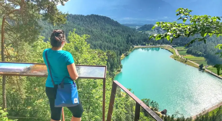 Donna ammira il lago turchese durante una passeggiata della merlonga, con montagne sullo sfondo.