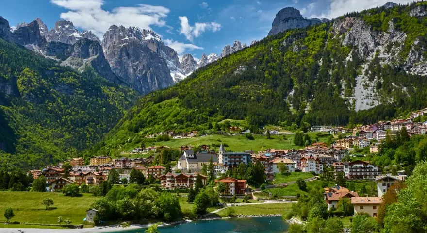 Villaggio alpino con case colorate e lago azzurro, incastonato tra montagne verdi e innevate. Ecco cosa vedere a Molveno per un panorama mozzafiato.