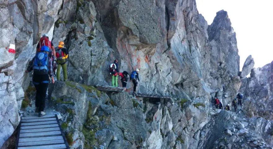 Escursionisti su un sentiero attrezzato, un'avventura di trekking in Adamello tra rocce e passerelle di legno.