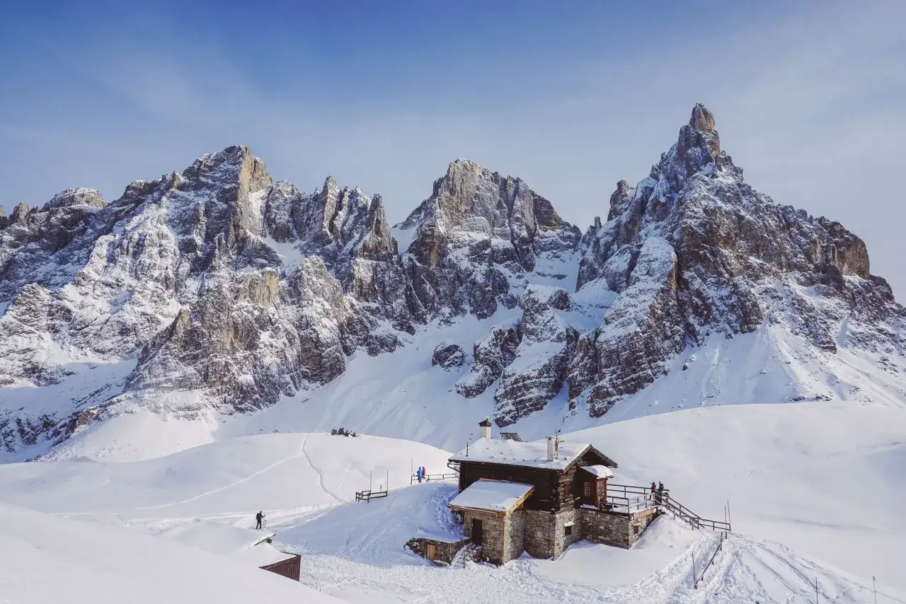 Rifugio innevato in Val Venegia, con imponenti vette dolomitiche sullo sfondo.